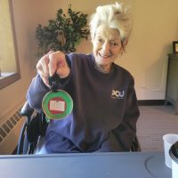 Senior woman holding up a Christmas ornament that she made.