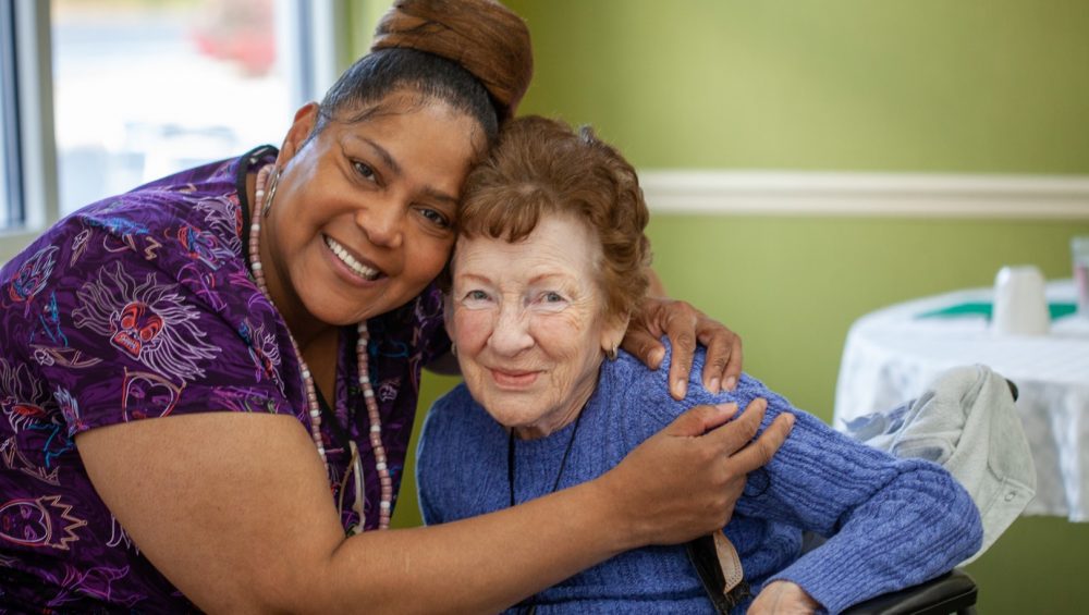 Caregiver and senior woman patient hugging