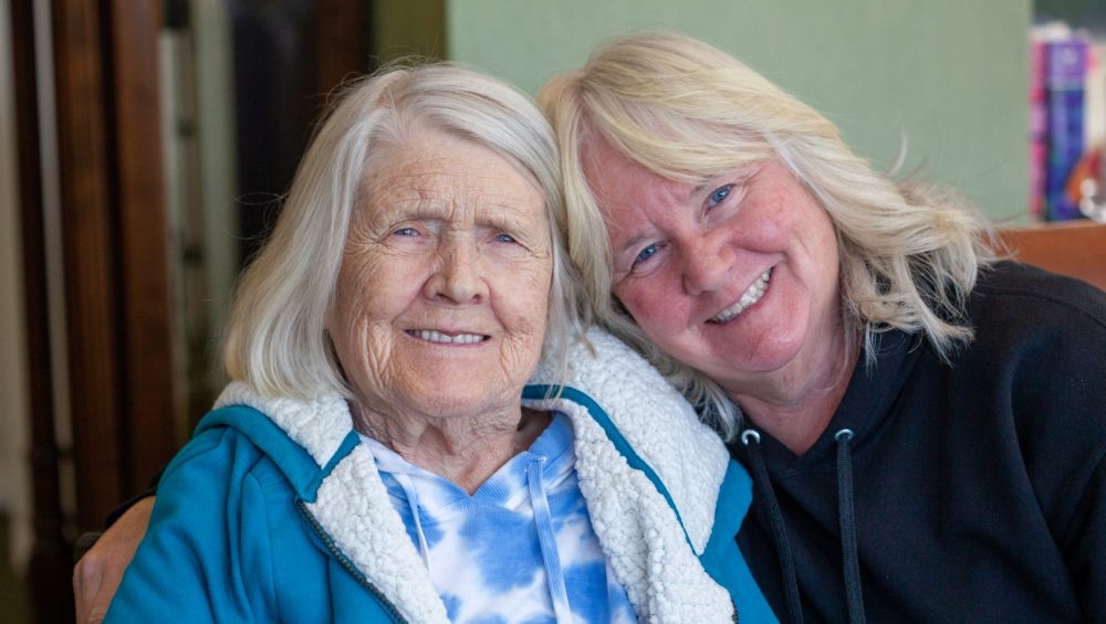 Elderly female Manoogian Manor resident with her daughter smiling for the camera.