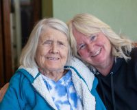 Elderly female Manoogian Manor resident with her daughter smiling for the camera.