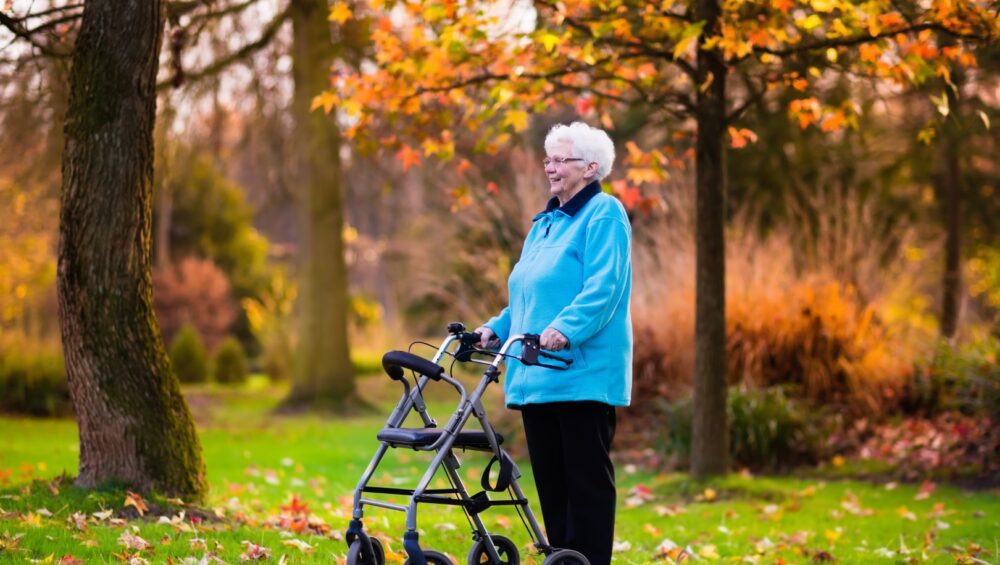 Elderly woman with rollator walker enjoying the fall