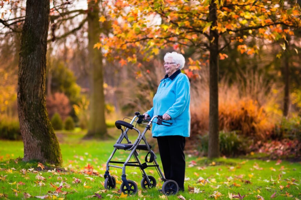 Elderly woman with rollator walker enjoying the fall