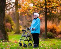 Elderly woman with rollator walker enjoying the fall