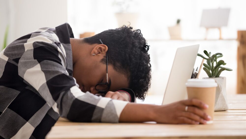 Exhausted African American woman falling asleep sleeping at laptop computer