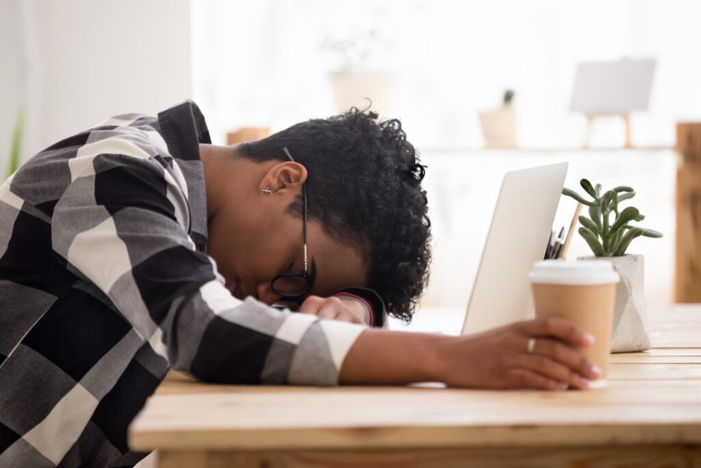 Exhausted African American woman falling asleep sleeping at laptop computer