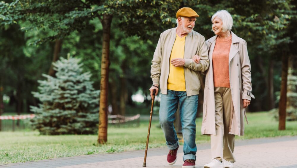 Senior couple smiling while walking on path in park