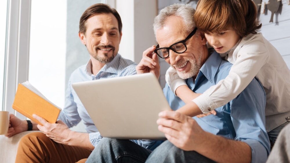 Young man and boy showing elderly man something on a tablet computer