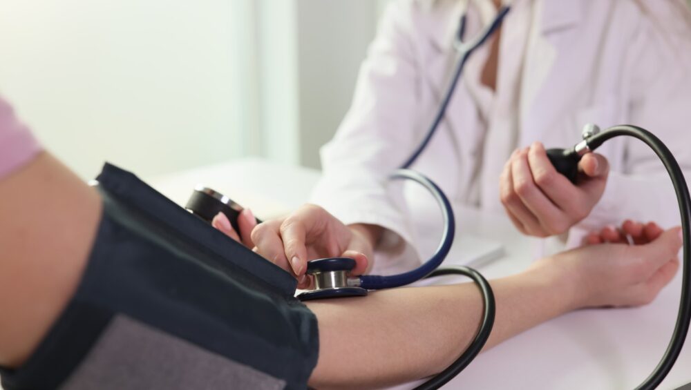 Nurse checking blood pressure with blood pressure cuff