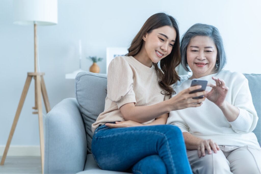 A young Asian woman helping an elderly Asian woman with her cellphone