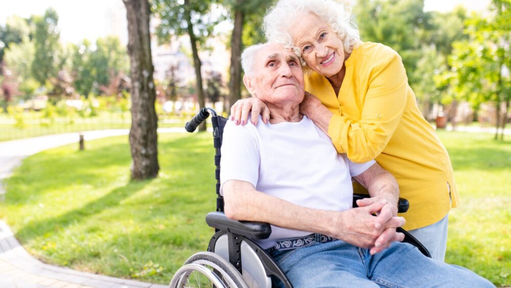 Senior woman hugging senior man in wheelchair