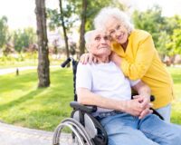 Senior woman hugging senior man in wheelchair