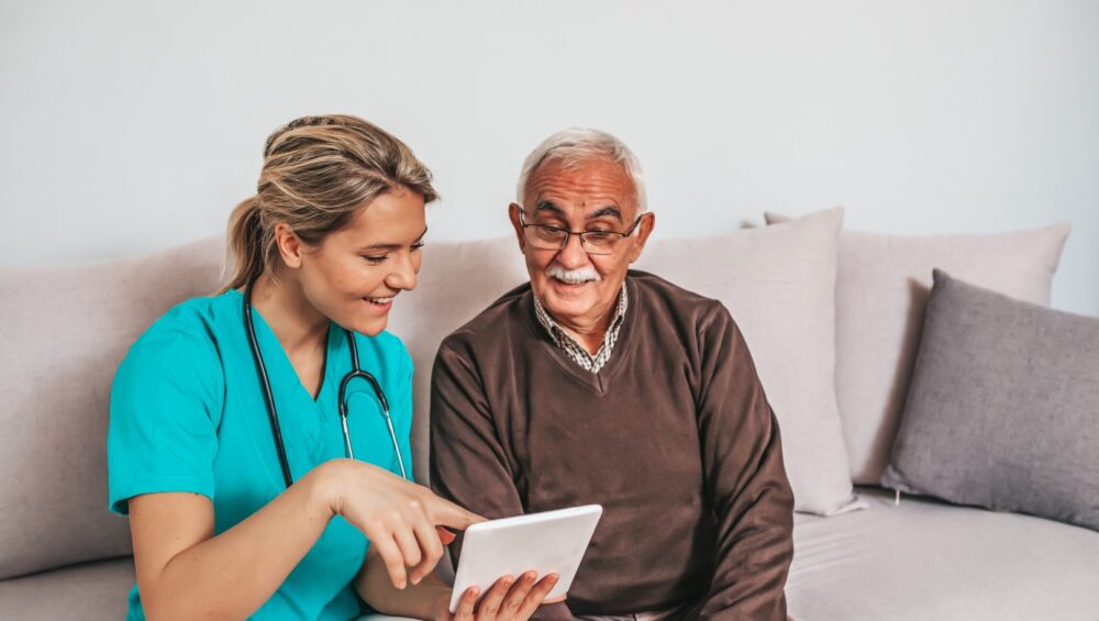 Assisted living resident with caregiver using a tablet computer