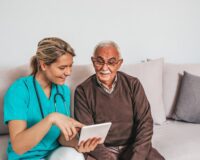 Assisted living resident with caregiver using a tablet computer