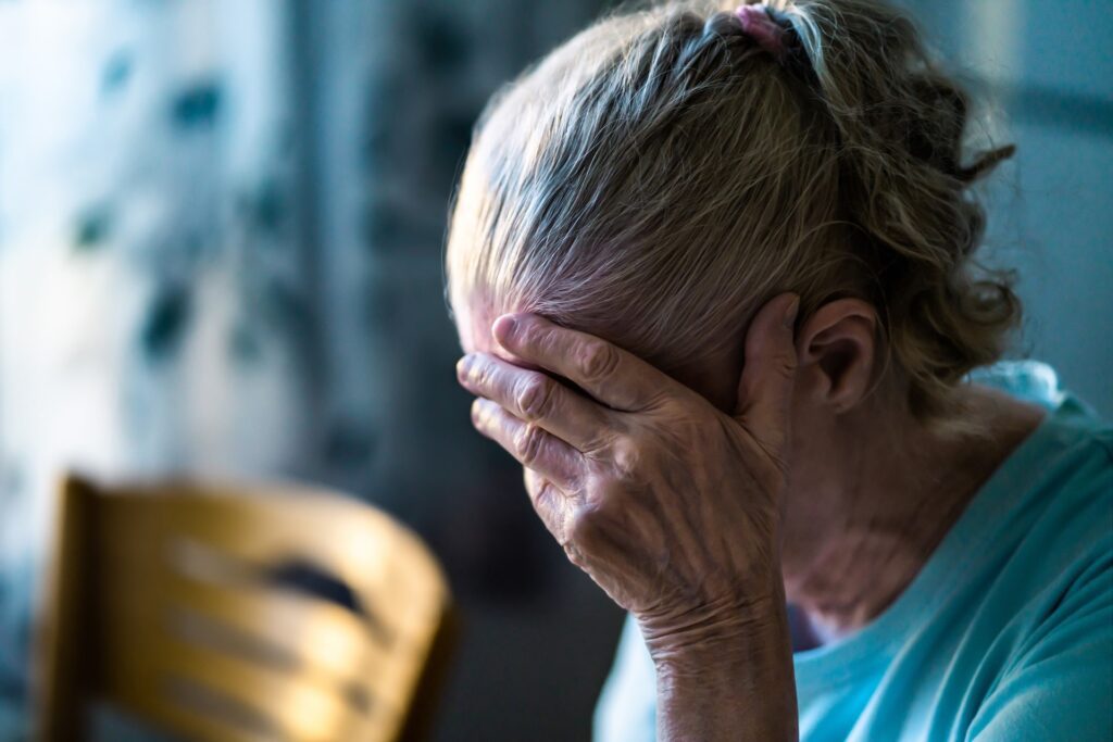 elderly woman holding her head trying to remember