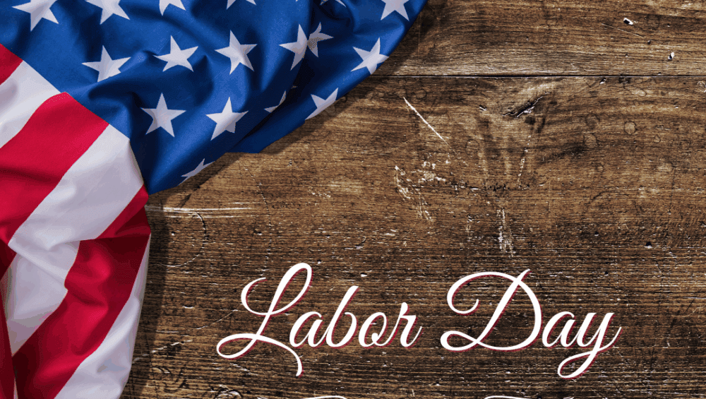 Close-up of an American flag draped over a rustic wooden surface with the words 'Labor Day' elegantly written in white script.