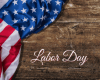 Close-up of an American flag draped over a rustic wooden surface with the words 'Labor Day' elegantly written in white script.