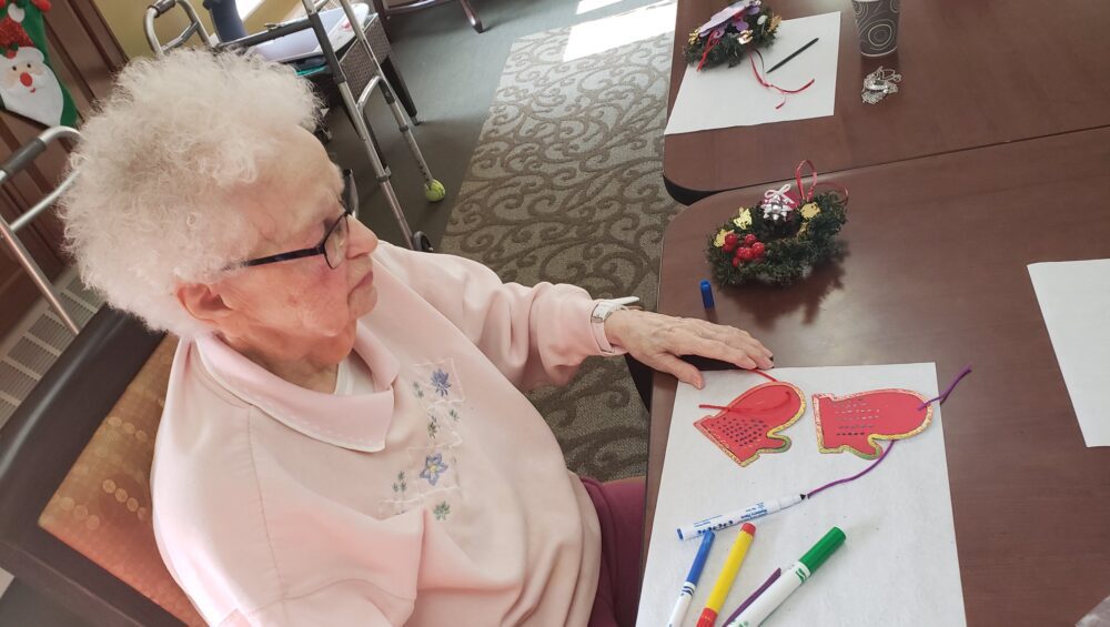 elderly woman making a Christmas craft at Manoogian Manor