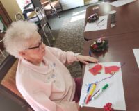 elderly woman making a Christmas craft at Manoogian Manor